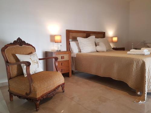 ein Schlafzimmer mit einem Bett und einem Stuhl sowie einem Bett mit einer Kommode in der Unterkunft Dúplex Palacio del Vizconde in Córdoba