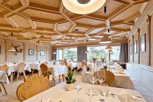 un restaurante con mesas y sillas blancas y ventanas en Granpanorama Hotel StephansHof, en Villandro