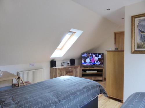 a attic room with a bed and a tv at Clifton Cottage B&B in Tyndrum