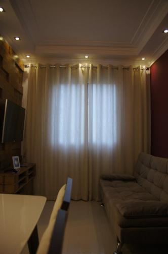 a living room with a couch and a large window at Apartamento Completo em Cotia - SP in Cotia