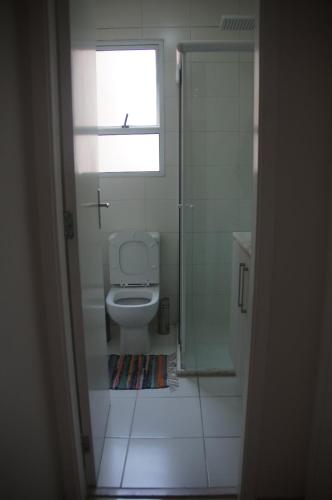 a bathroom with a toilet and a window and a shower at Apartamento Completo em Cotia - SP in Cotia