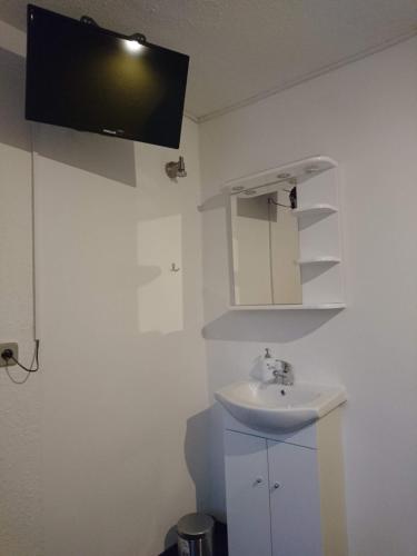 a bathroom with a sink and a tv on the wall at Penzion Forest in Rozvadov