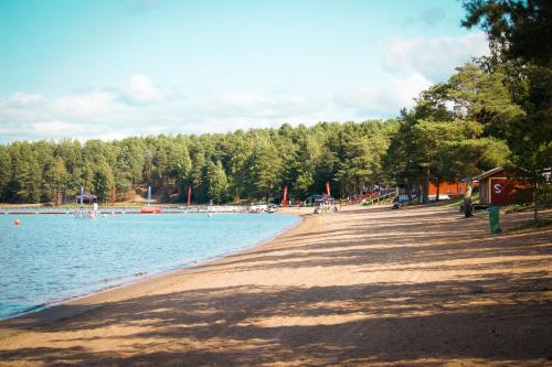 a beach with people sitting on the sand and water at Årsunda Strandbad Sjösunda vandrarhem in Årsunda