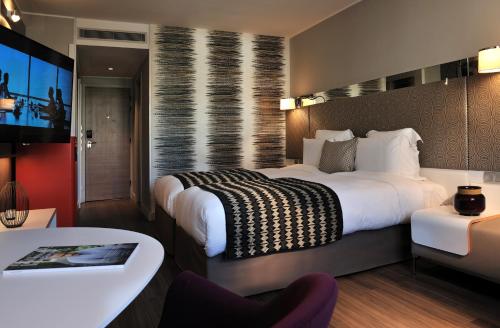 a hotel room with a large bed and a table at Pullman Dakar Teranga in Dakar