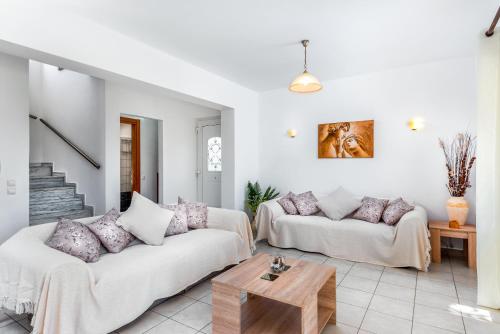 Una sala de estar con dos sofás blancos y una mesa. en Afrodite Classico Villa, en Kolymbia