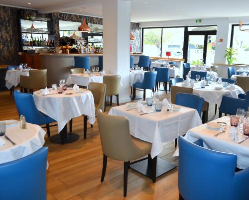 a restaurant with white tables and blue chairs at Le Galion Hotel et Restaurant Canet Plage - Logis in Canet-en-Roussillon