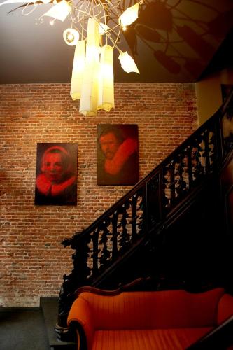 a room with portraits on a brick wall with a couch at Hotel Harmony in Ghent