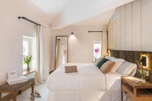 a white bedroom with a large bed and a table at Boutique Hotel Sant Roc & Spa in Mahón