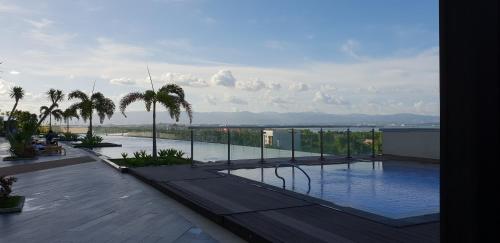 a swimming pool with palm trees on a building at Mactan Newtown Ocean View 360 Degree in Mactan