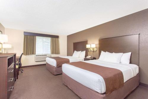 a hotel room with two beds and a desk at AmericInn by Wyndham Rhinelander in Rhinelander