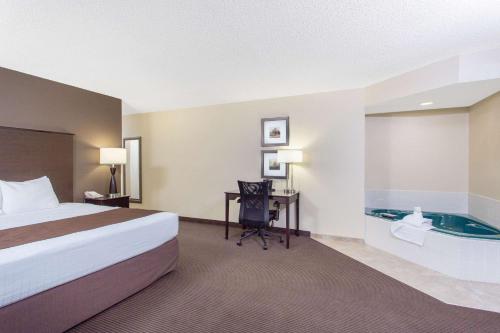 a hotel room with a bed and a desk and a tub at AmericInn by Wyndham Rhinelander in Rhinelander