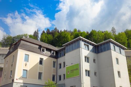 a white building with a blue roof and a blue sky at Hostel Marmota in Innsbruck