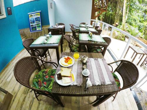 a patio with tables and chairs with food on it at Pousada Guapuruvu in Abraão