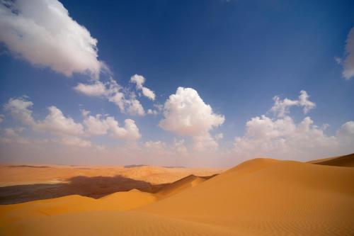 a desert with sand dunes and clouds in the sky at Anantara Qasr al Sarab Desert Resort in Jurayrah