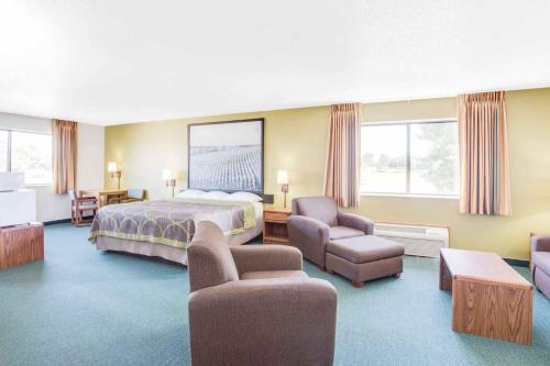 Cette grande chambre comprend un lit et des chaises. dans l'établissement Super 8 by Wyndham Oelwein, à Oelwein