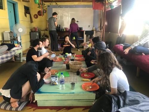 a group of people sitting around a table eating food at The Little Blue Window Hostel in Bengaluru