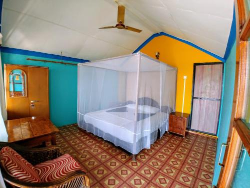 a bedroom with a bed with a mosquito net at Sealand Beach Cottages in Patnem
