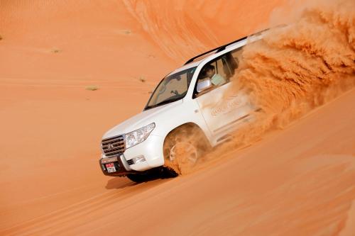 a white truck driving through the sand in the desert at Anantara Qasr al Sarab Desert Resort in Jurayrah
