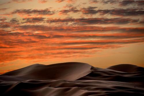 a desert with a sunset in the background at Anantara Qasr al Sarab Desert Resort in Jurayrah
