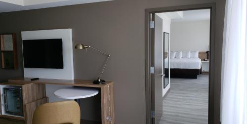 a room with a desk with a television and a bed at Wyndham Garden Ft Lauderdale Airport & Cruise Port in Dania Beach