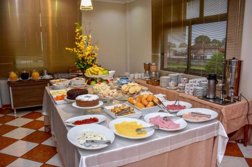 a long table with a buffet of food on it at Hotel Plaza Sul in Caràzinho