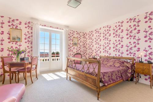 a bedroom with pink floral wallpaper and a bed and a table at Hotel Les Goelands in Saint-Jean-de-Luz