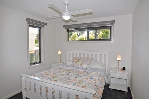 a white bedroom with a bed and a ceiling fan at SUNSET WATERS - INLET SIDE in Inverloch