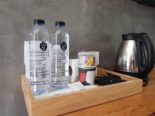 a wooden tray with two bottles of water and a coffee maker at Beloft Hotel in Nakhon Si Thammarat