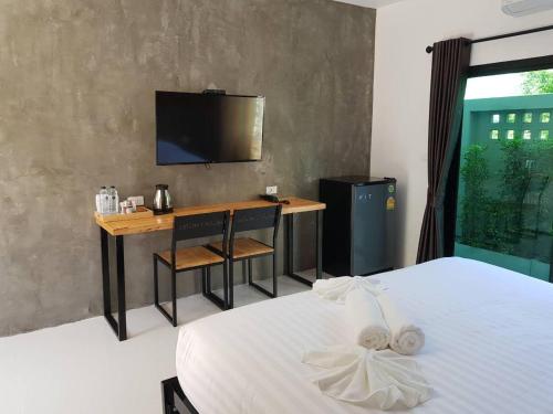 een slaapkamer met een bed, een bureau en een televisie bij Beloft Hotel in Nakhon Si Thammarat
