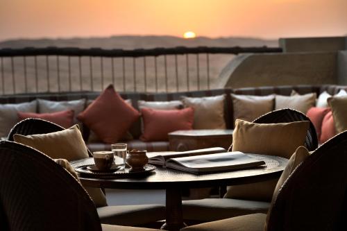 a table and chairs with a table and a couch at Anantara Qasr al Sarab Desert Resort in Jurayrah