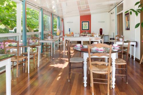 ein Esszimmer mit Tischen und Stühlen und Fenstern in der Unterkunft Hotel Les Goelands in Saint-Jean-de-Luz