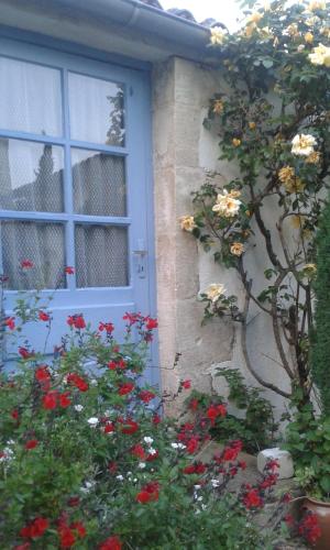 a house with a blue door and some red flowers at LA MAISON BLEUE in Saint-Gelais