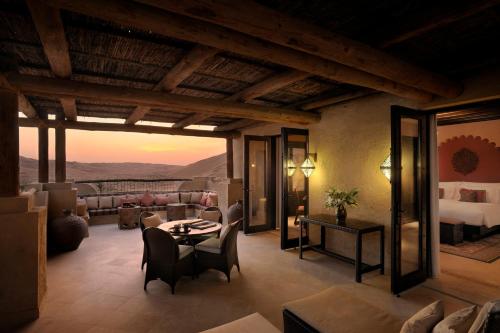 a hotel room with a bed and a table and chairs at Anantara Qasr al Sarab Desert Resort in Jurayrah