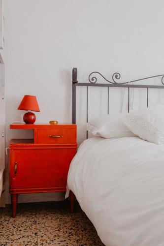 a bed with a red dresser with a red lamp on it at Agriturismo Le Piagge in Ponzone