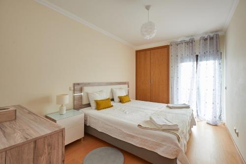 a white bedroom with a large bed with yellow pillows at BeGuest Cascais Inn Apartments in Cascais
