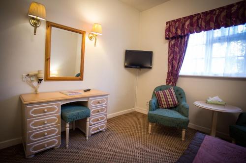 a room with a dresser and a mirror and a chair at Marston Farm Hotel in Sutton Coldfield