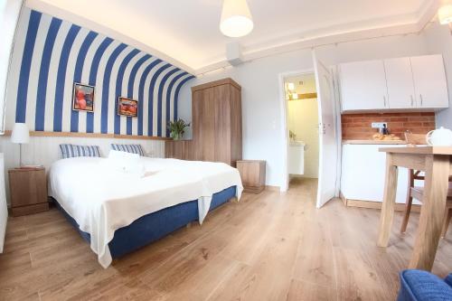 a bedroom with a bed and a blue and white striped wall at Mistral Ustka in Ustka