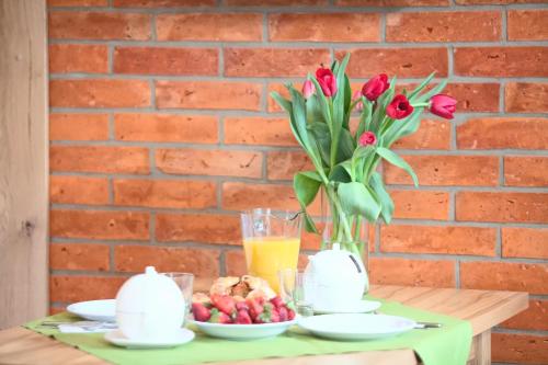 a table with a vase of red tulips and fruit at Mistral Ustka in Ustka