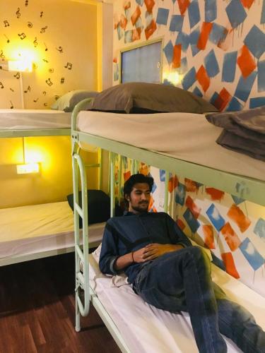 a man sitting on top of two bunk beds at The Little Blue Window Hostel in Bengaluru