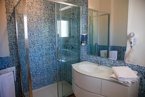 y baño con ducha acristalada y lavamanos. en Hotel La Contessa, en Santa Teresa Gallura