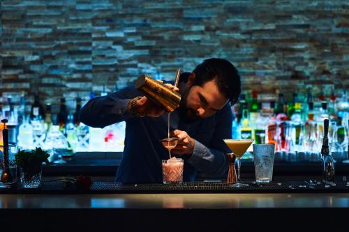 a man is making a drink at a bar at Hotel Bosco in Kingston upon Thames