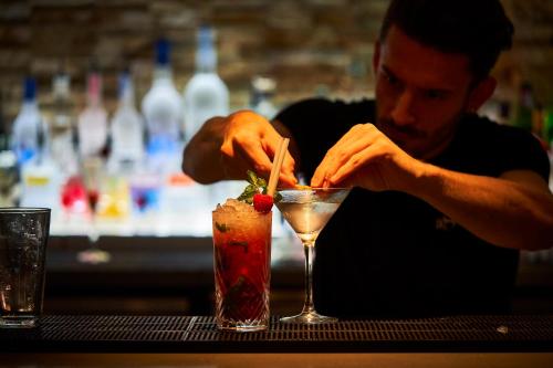 a man is making a drink at a bar at Hotel Bosco in Kingston upon Thames