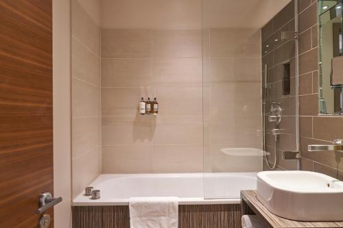 ein Badezimmer mit einer Badewanne und einem Waschbecken in der Unterkunft Hotel Bosco in Kingston upon Thames