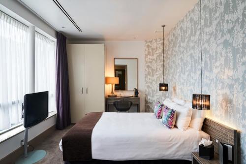 ein Hotelzimmer mit einem Bett und einem TV in der Unterkunft Hotel Bosco in Kingston upon Thames