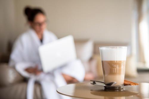 a cup of coffee on a table with a woman working on a laptop at Hotel & Spa Princesa Munia in Oviedo