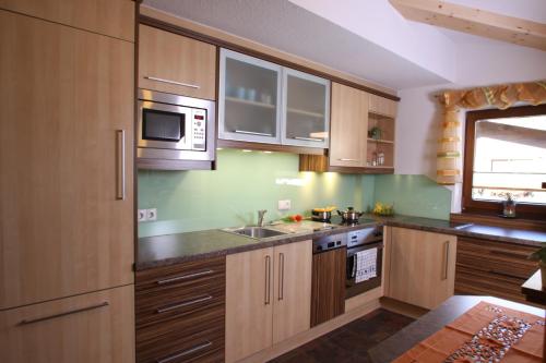 a kitchen with wooden cabinets and a microwave at Chalet Walzl in Längenfeld