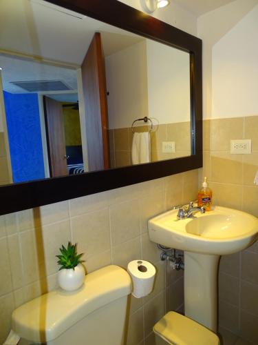 a bathroom with a sink and a toilet and a mirror at Jaco Beach Condos in Jacó