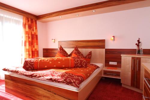 a bedroom with a wooden bed with red pillows at Chalet Walzl in Längenfeld