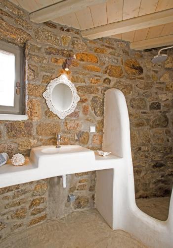 a bathroom with a stone wall with a sink at Amallini Suites Mykonos in Super Paradise Beach