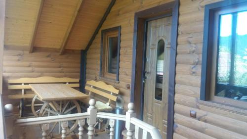 a porch of a log cabin with a table and bench at Котедж "Хата Рибака" in Kosiv